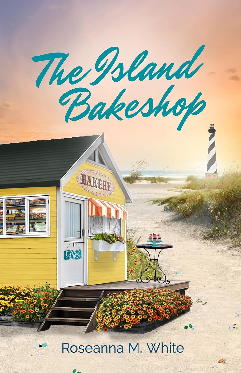 The Island Bakeshop Book cover for "The Island Bakeshop" by Roseanna M. White. The title is written in large teal script across a warm sunset sky. Below, a small yellow wooden bakery with an open pastry window stands on a sandy beach. A path winds through grassy dunes past a small bistro table with cupcakes, leading toward a prominent black-and-white spiral striped lighthouse near the ocean. The author's name is printed at the bottom.